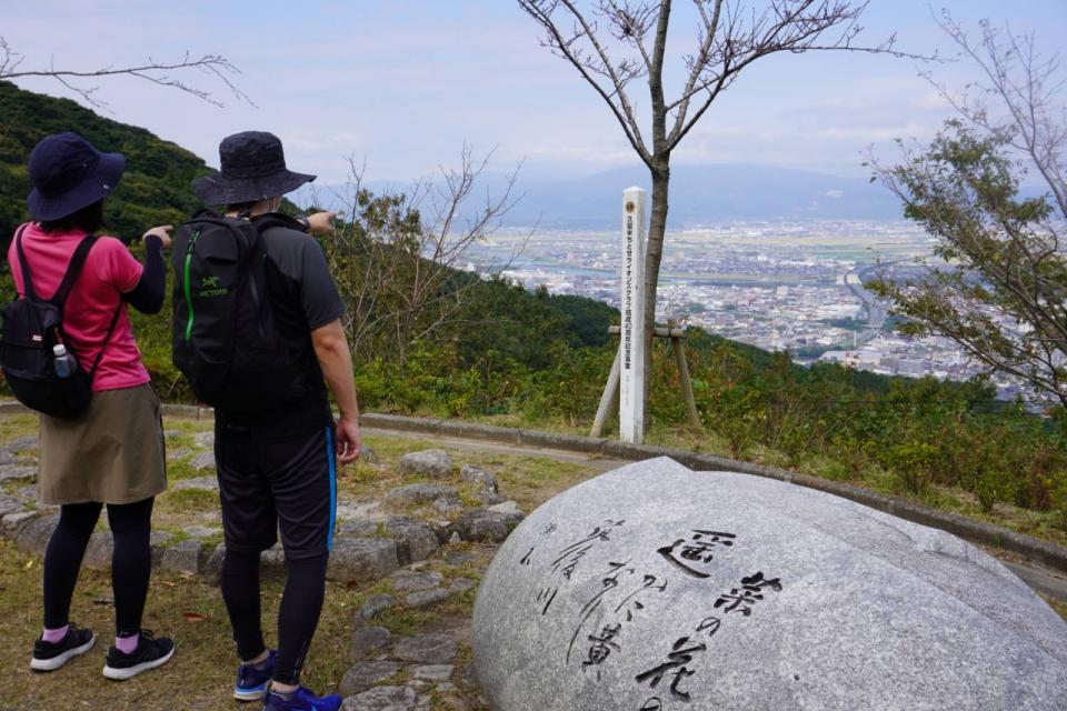 夏目漱石句碑と景色を眺めている人々の画像